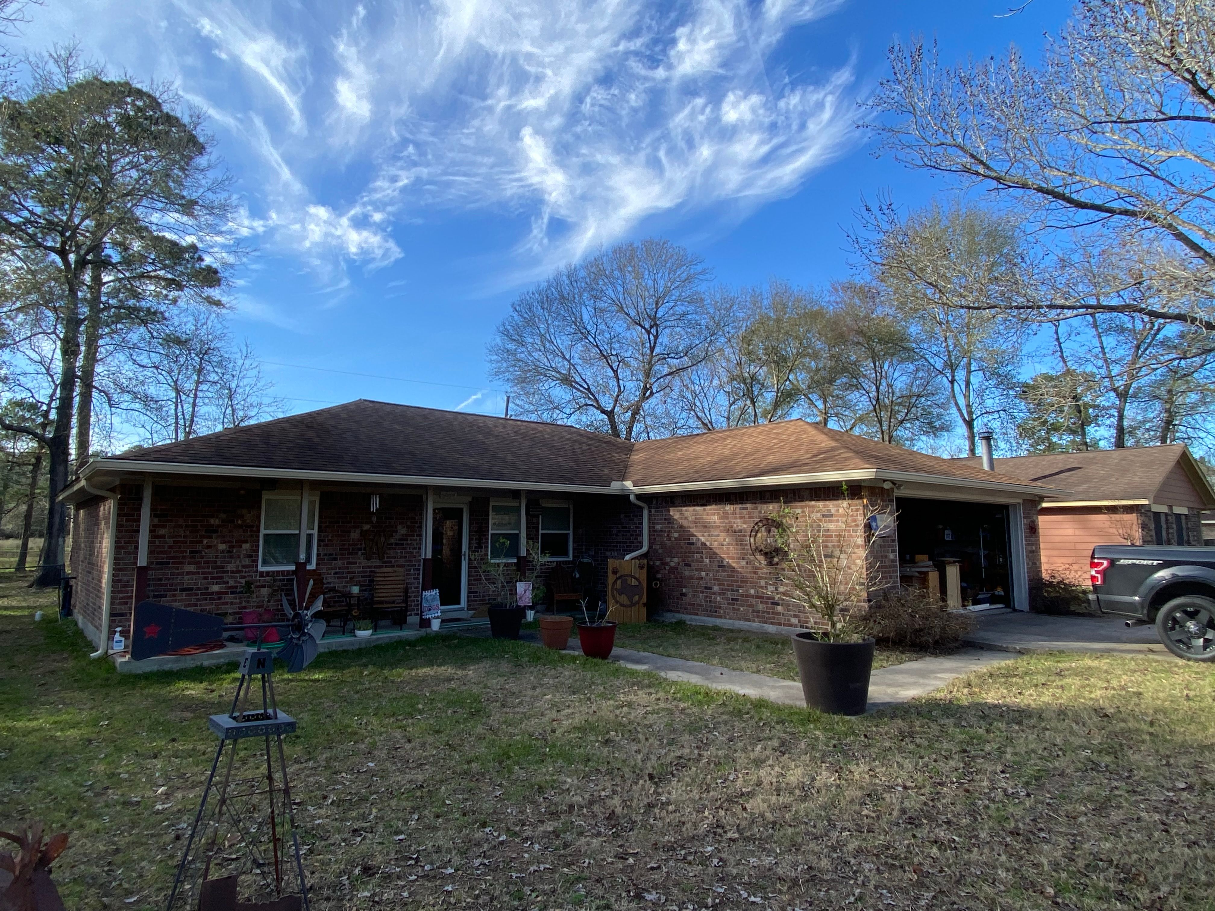 Wide view of cream seamless gutters and downspouts across a single-story brick home in Magnolia