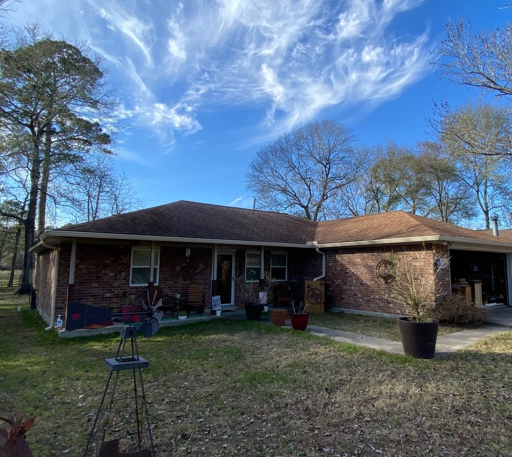 Wide view of cream seamless gutters and downspouts across a single-story brick home in Magnolia