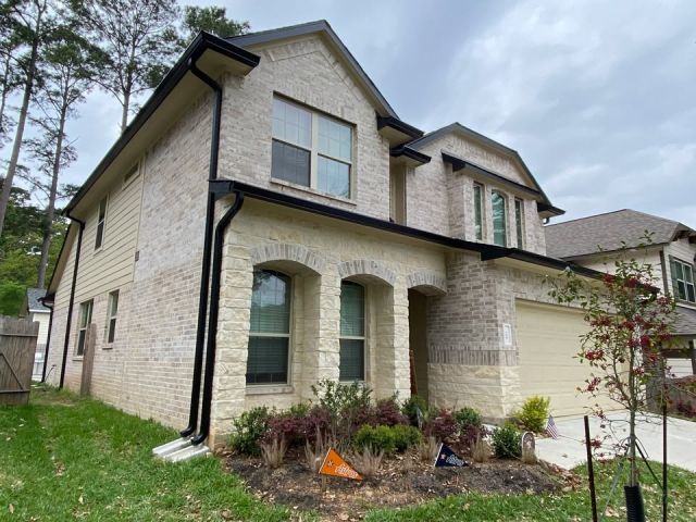 Black seamless gutters and downspouts outlining the two-story light-brick front of a Montgomery home