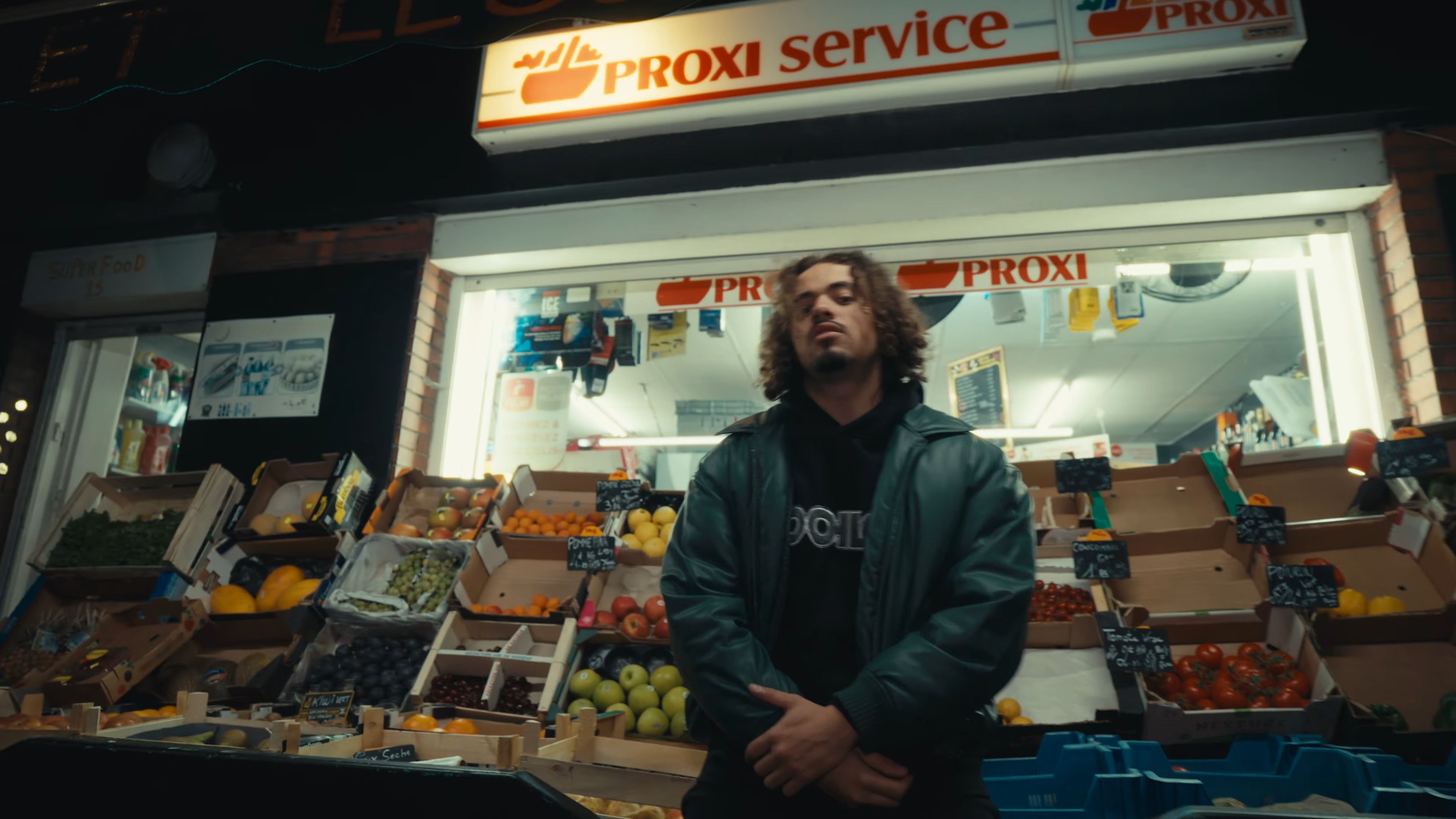 Plan ou l'artiste est adossé à l'étal de fruit