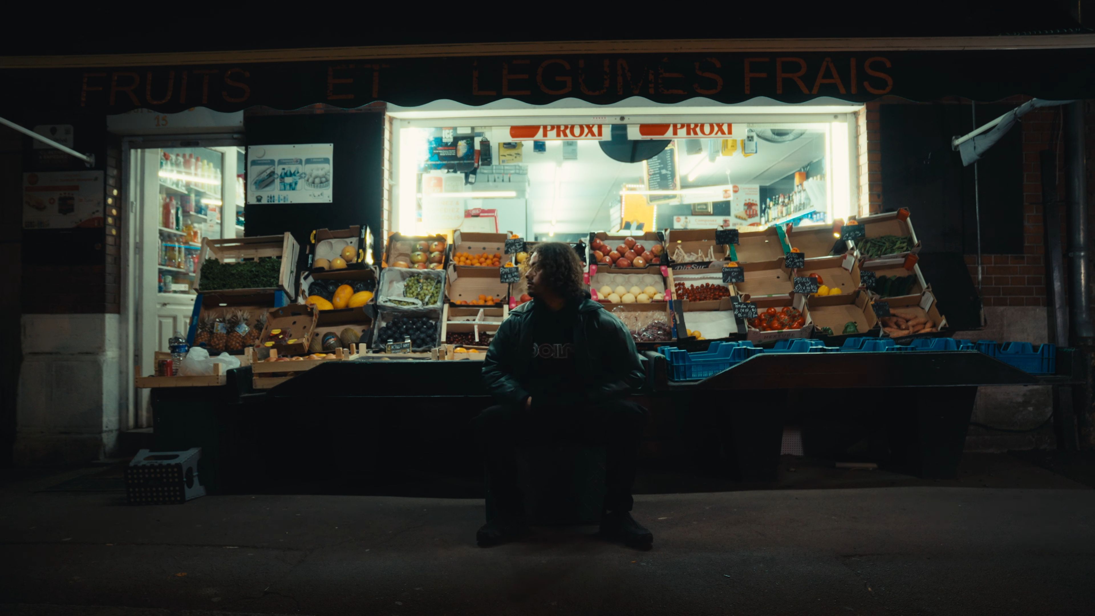 L'artiste est assis devant une épicerie