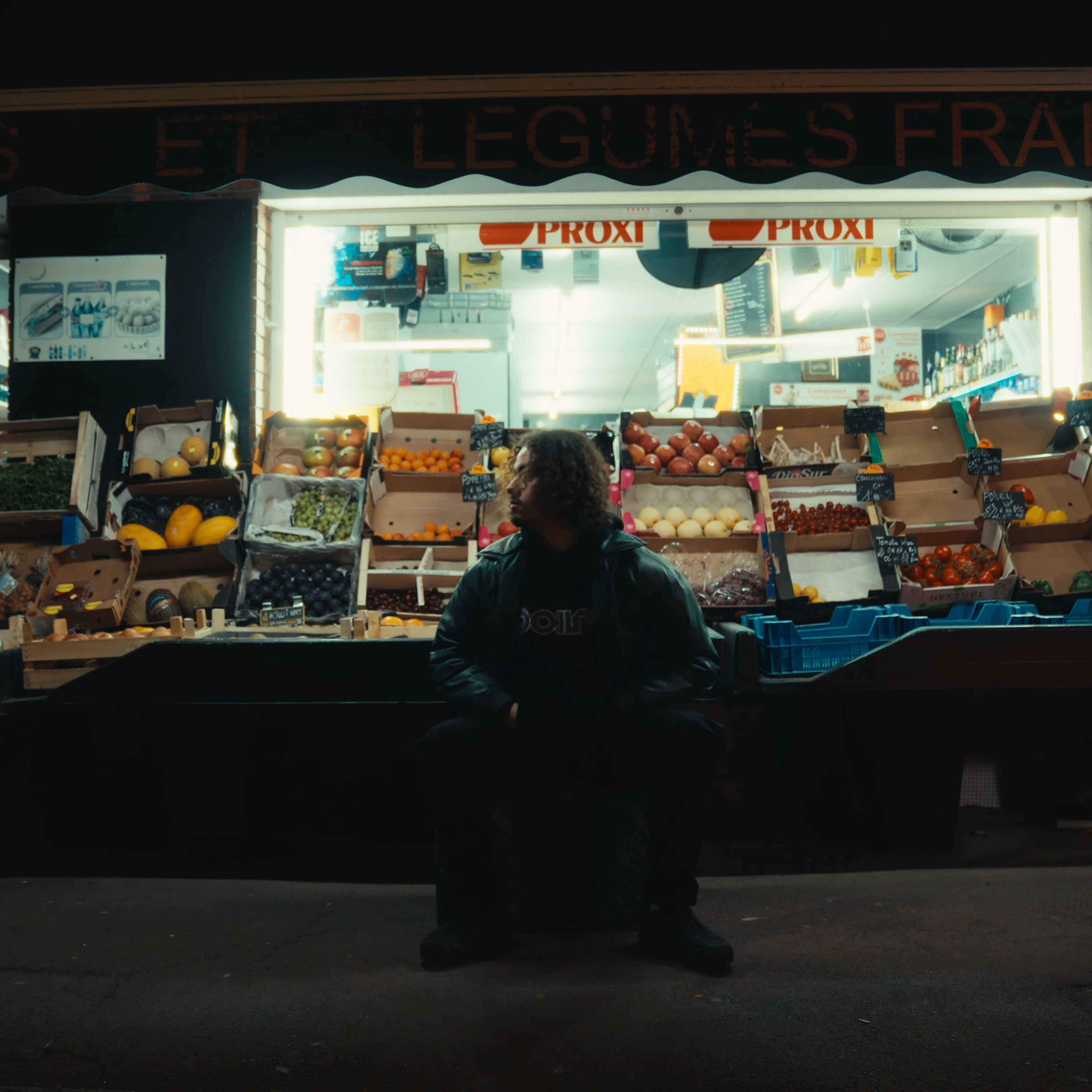L'artiste est assis devant une épicerie