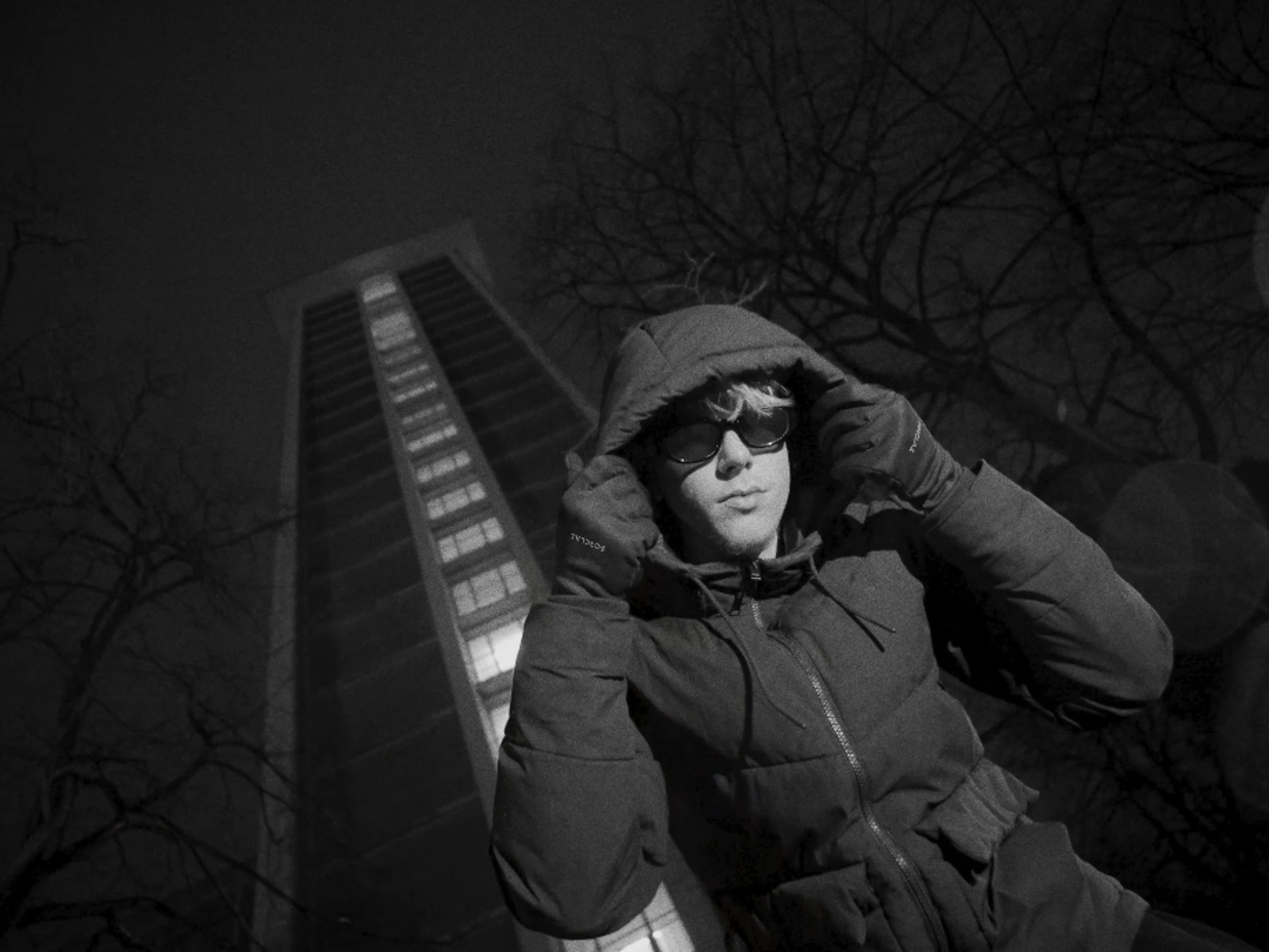 Plan en contre-plongée de l'artiste devant un bâtiment.