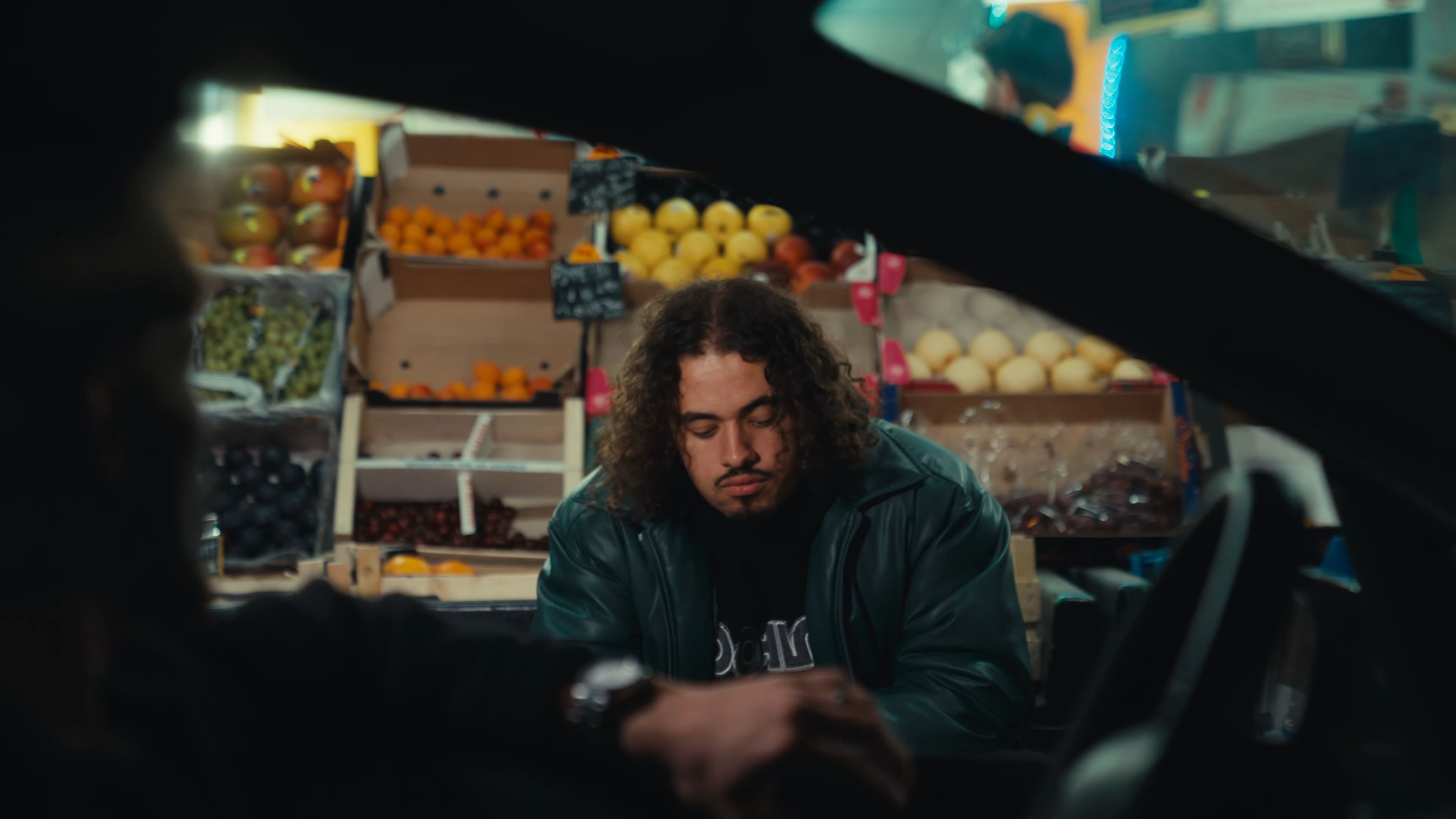 Plan serré ou l'artiste est visible au travers de la fenêtre d'une voiture