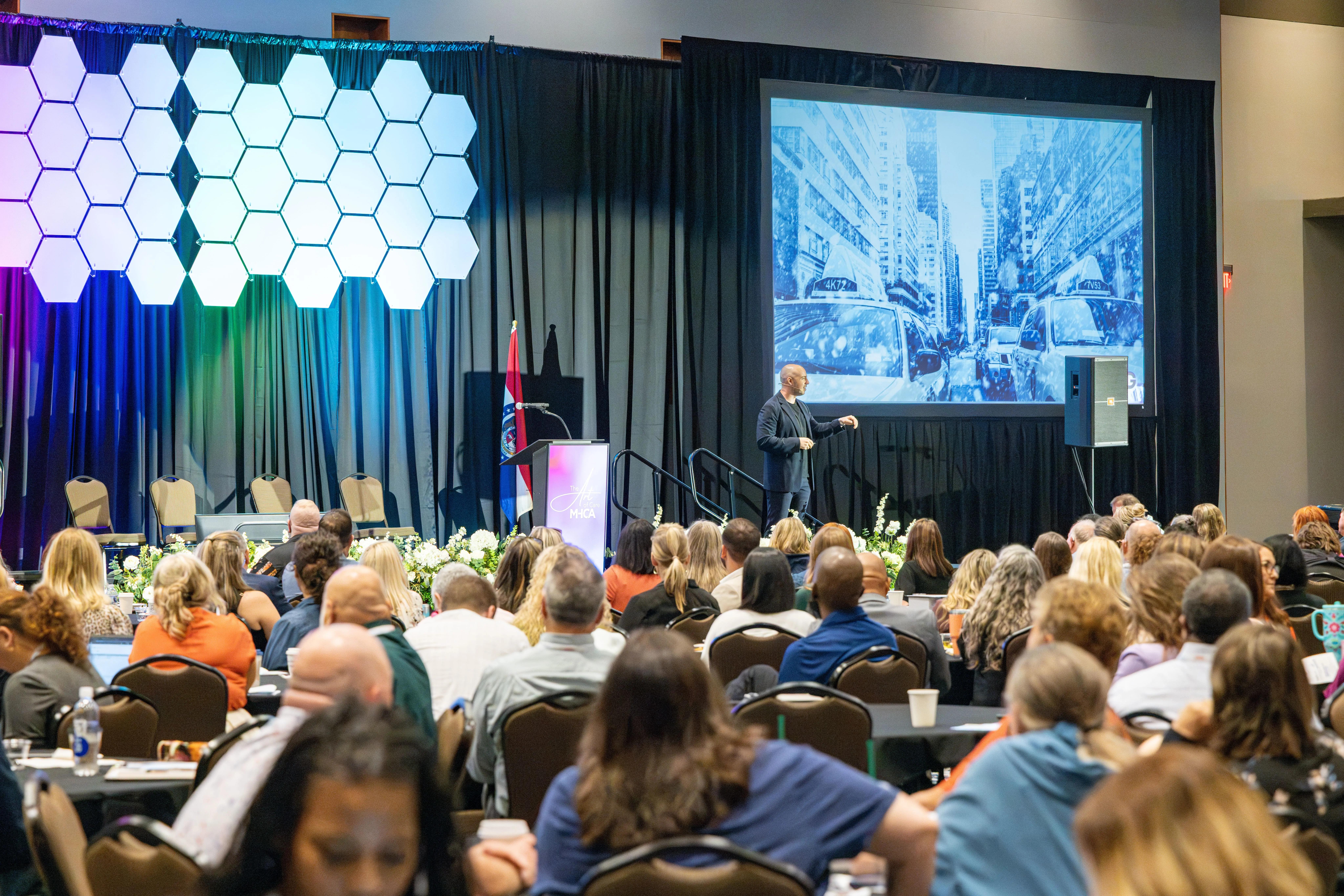 Danny Goldberg presenting on stage to a full room at a Missouri Health Care Association conference