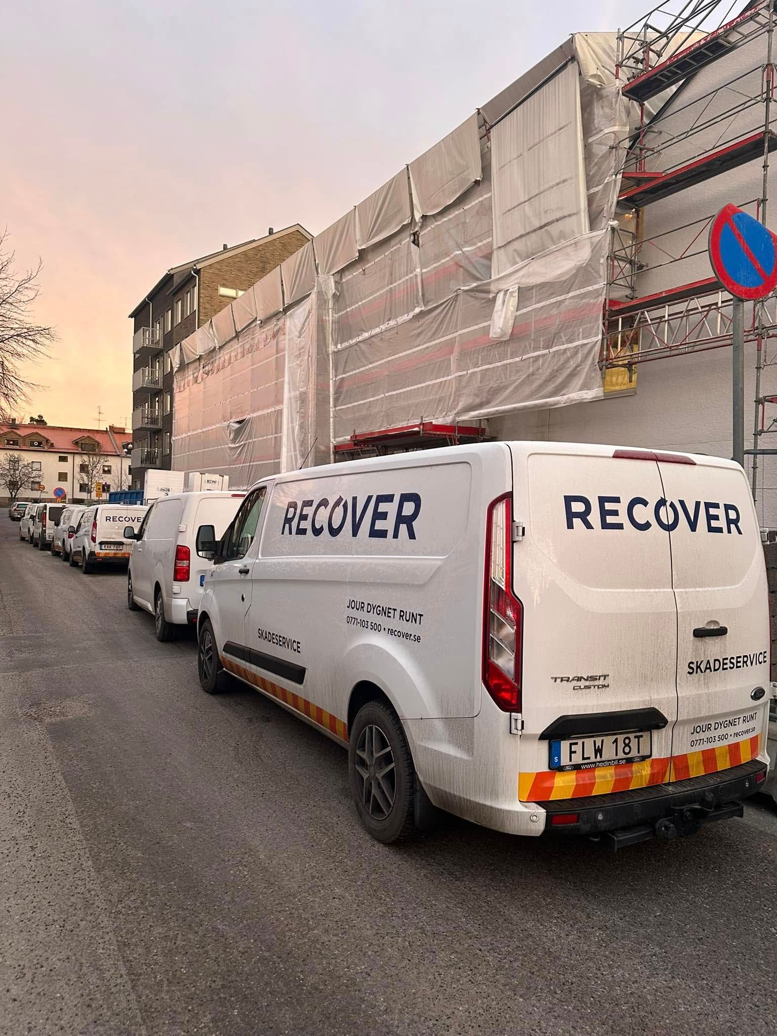 Recoverbilar framför byggnader