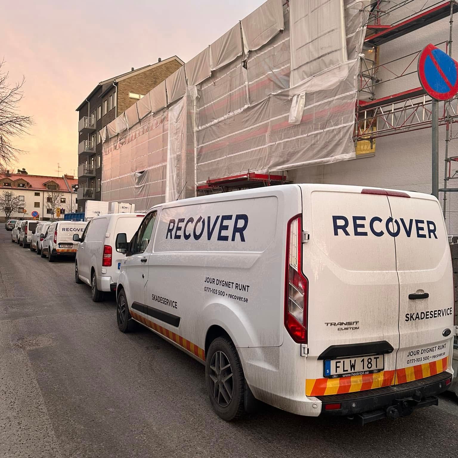 Recoverbilar framför byggnader