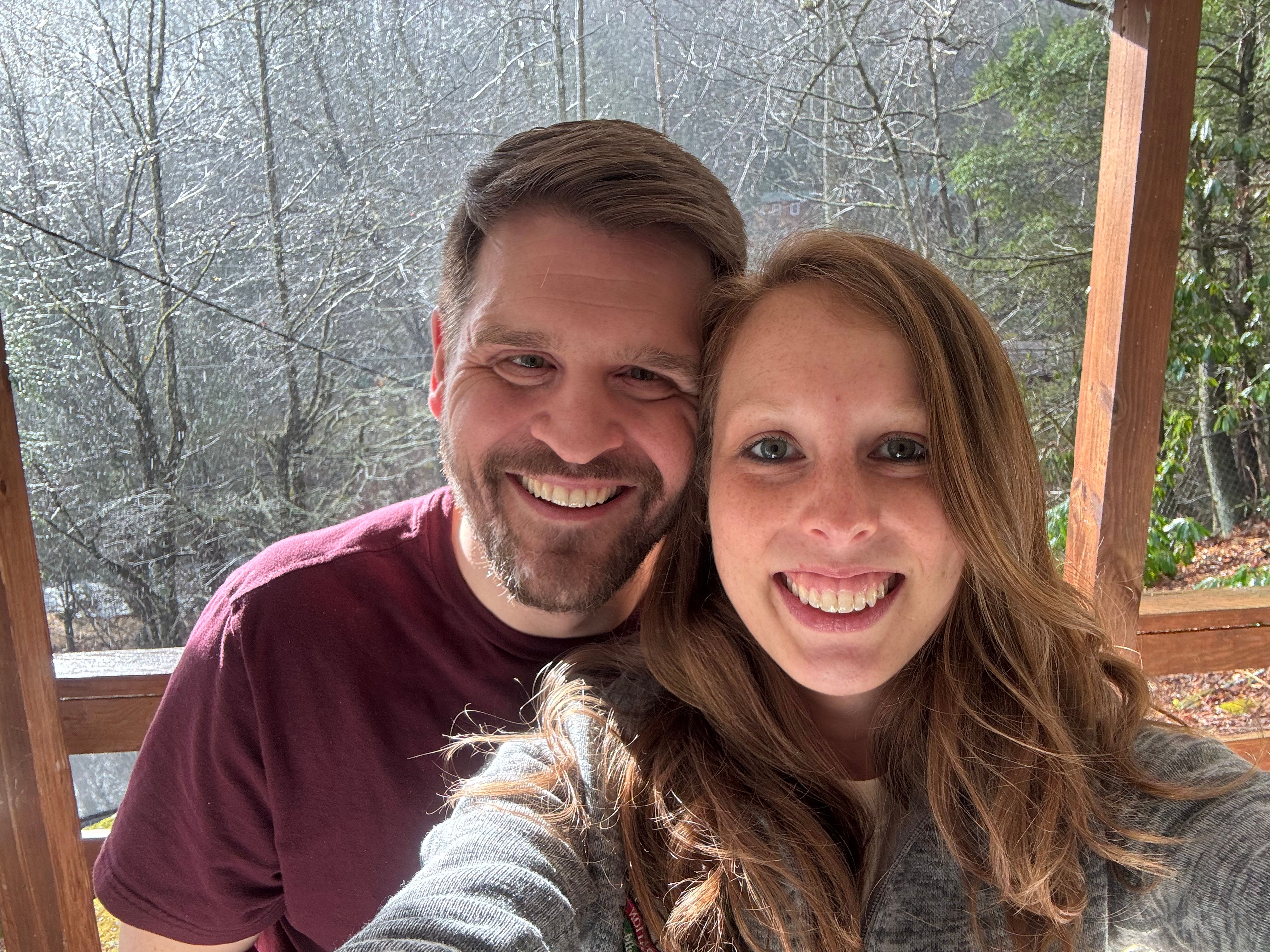 Amanda and Steven at home, snow on the trees behind them
