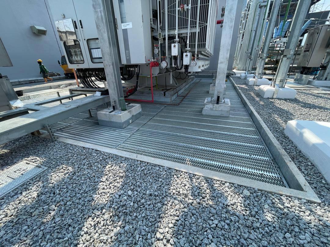 Safety grating walkway framed in steel along the transformer base