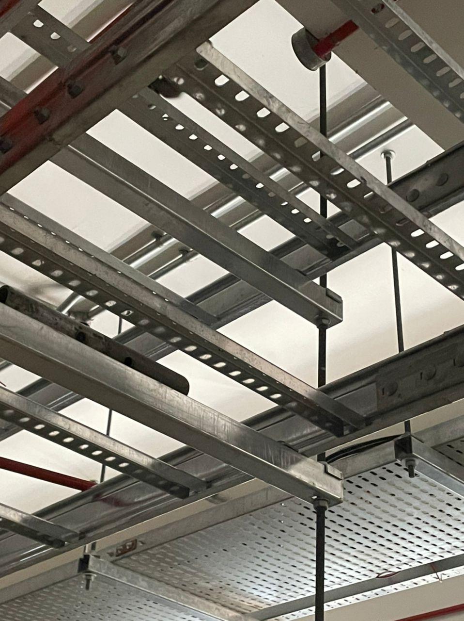 Underside of cable ladder rungs above perforated cable tray