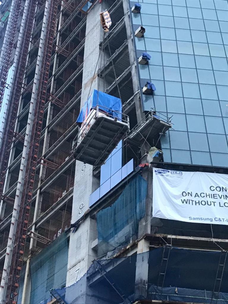 Loaded lifting platform being hoisted up the glass façade of the PNB 118 tower