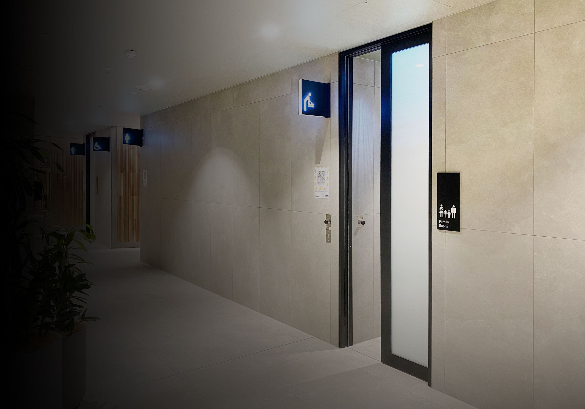 Outside of toilets that has an automatically opening door and illuminated signage