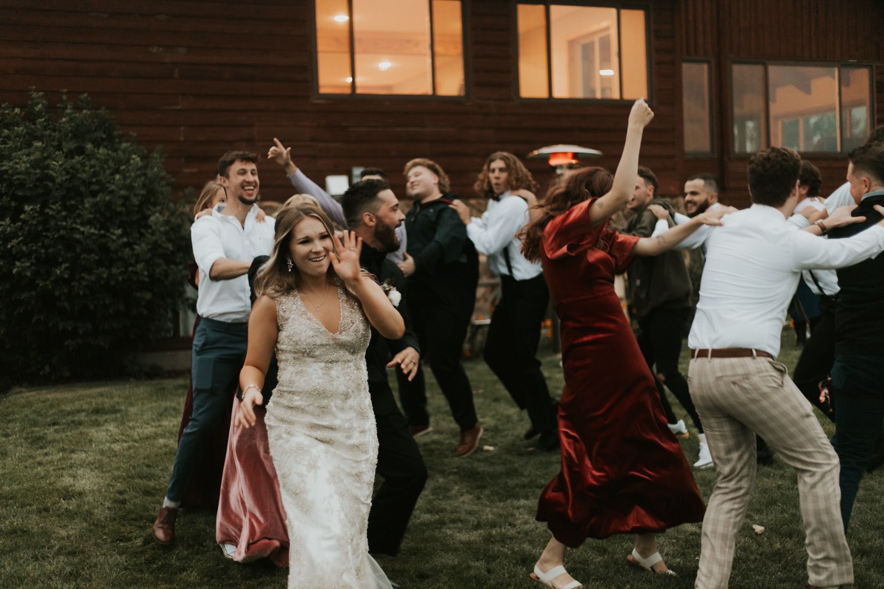 Bride leading guests in a dance on the lawn at dusk