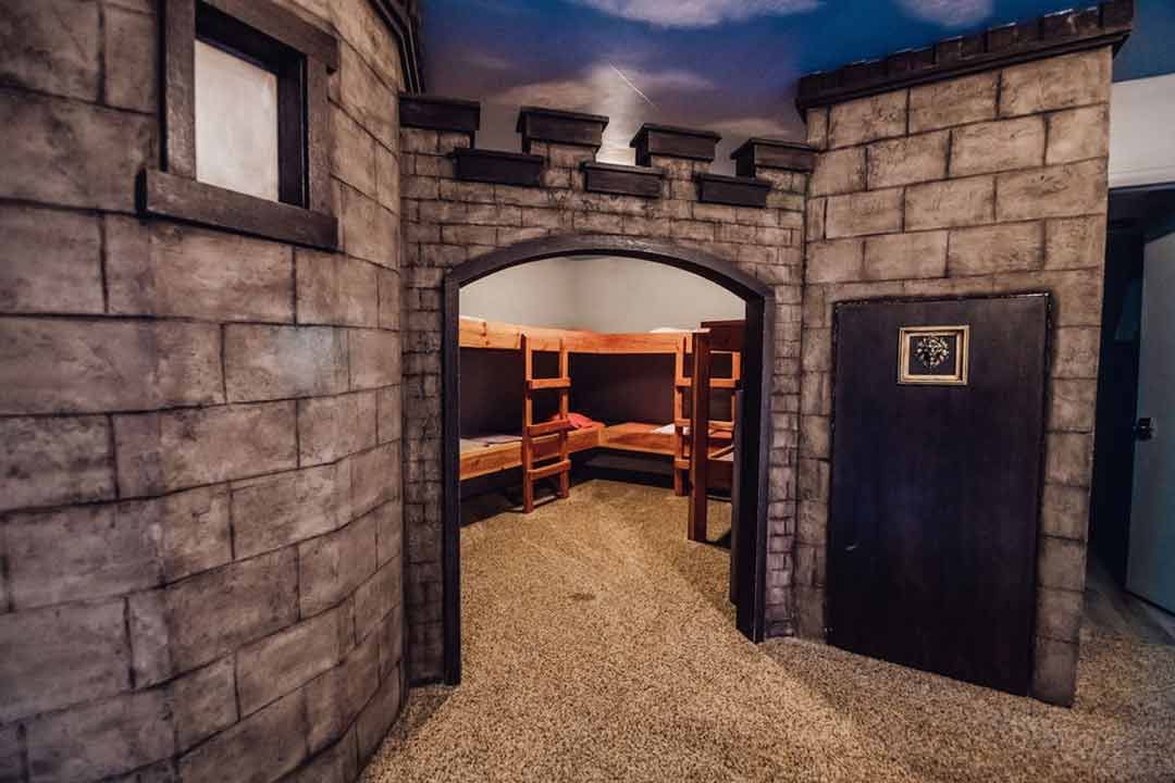 Castle-themed bunk room with stone archway and wooden bunks