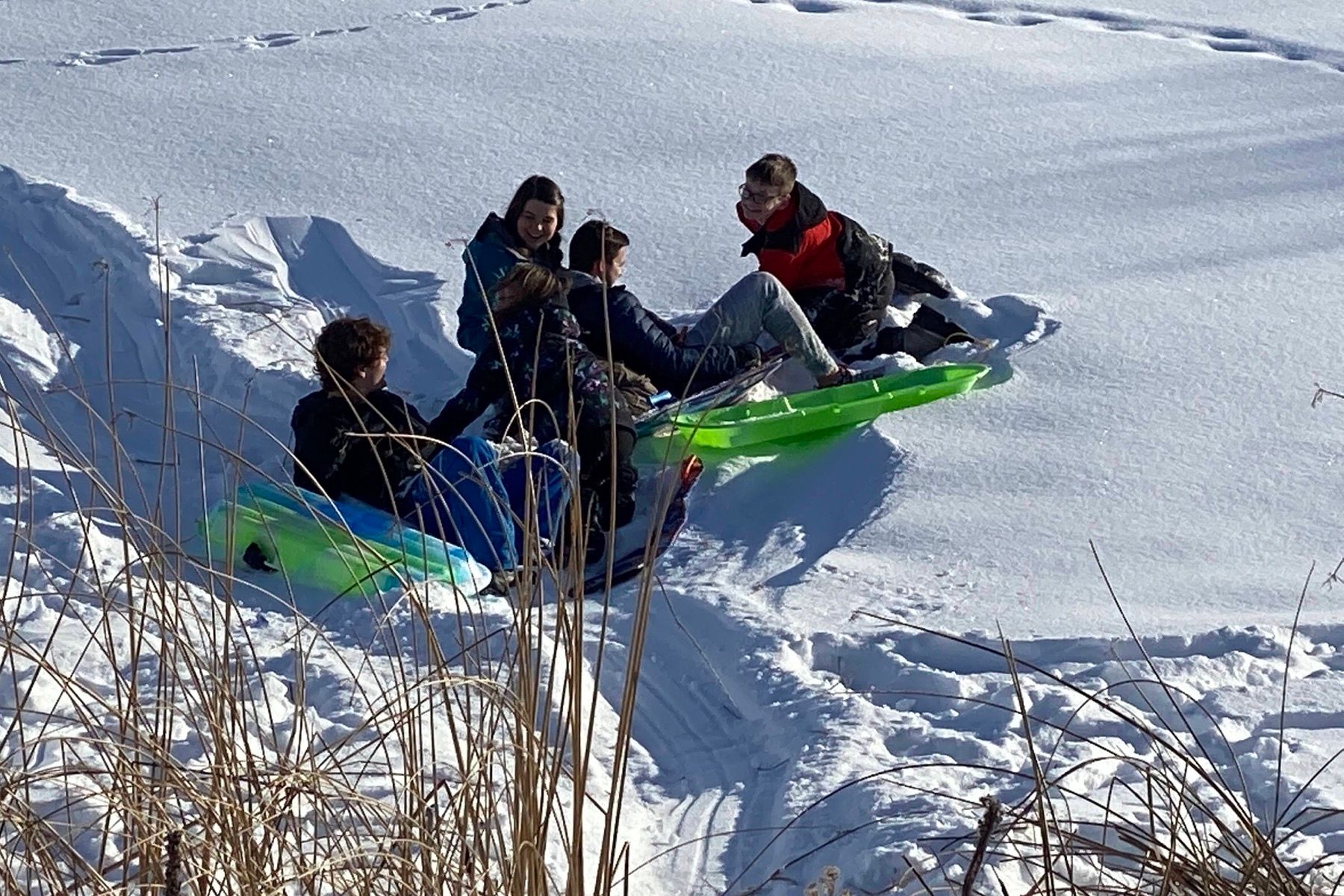 Family posed with sleds on a snowy hillside at the lodge