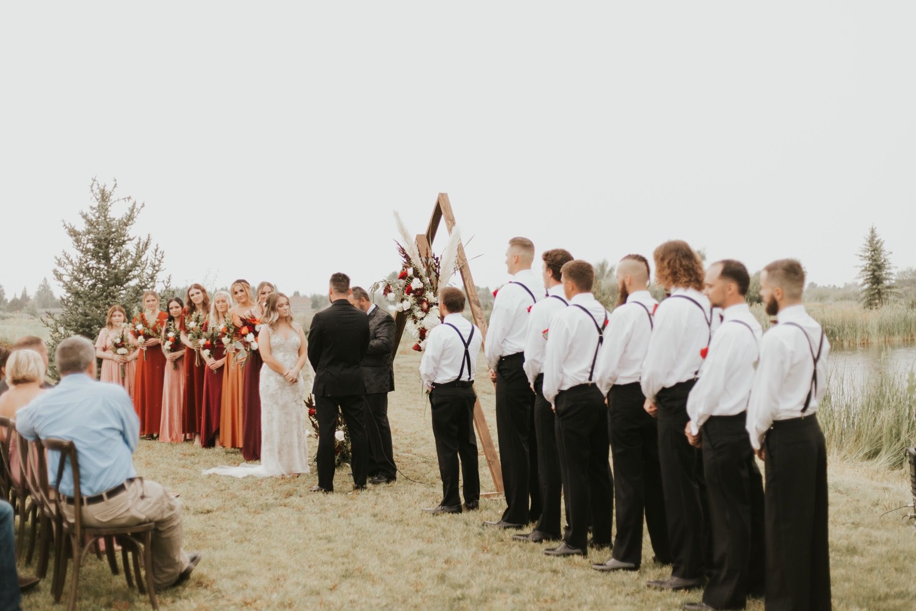 Wedding ceremony under a wooden A-frame arch on the meadow