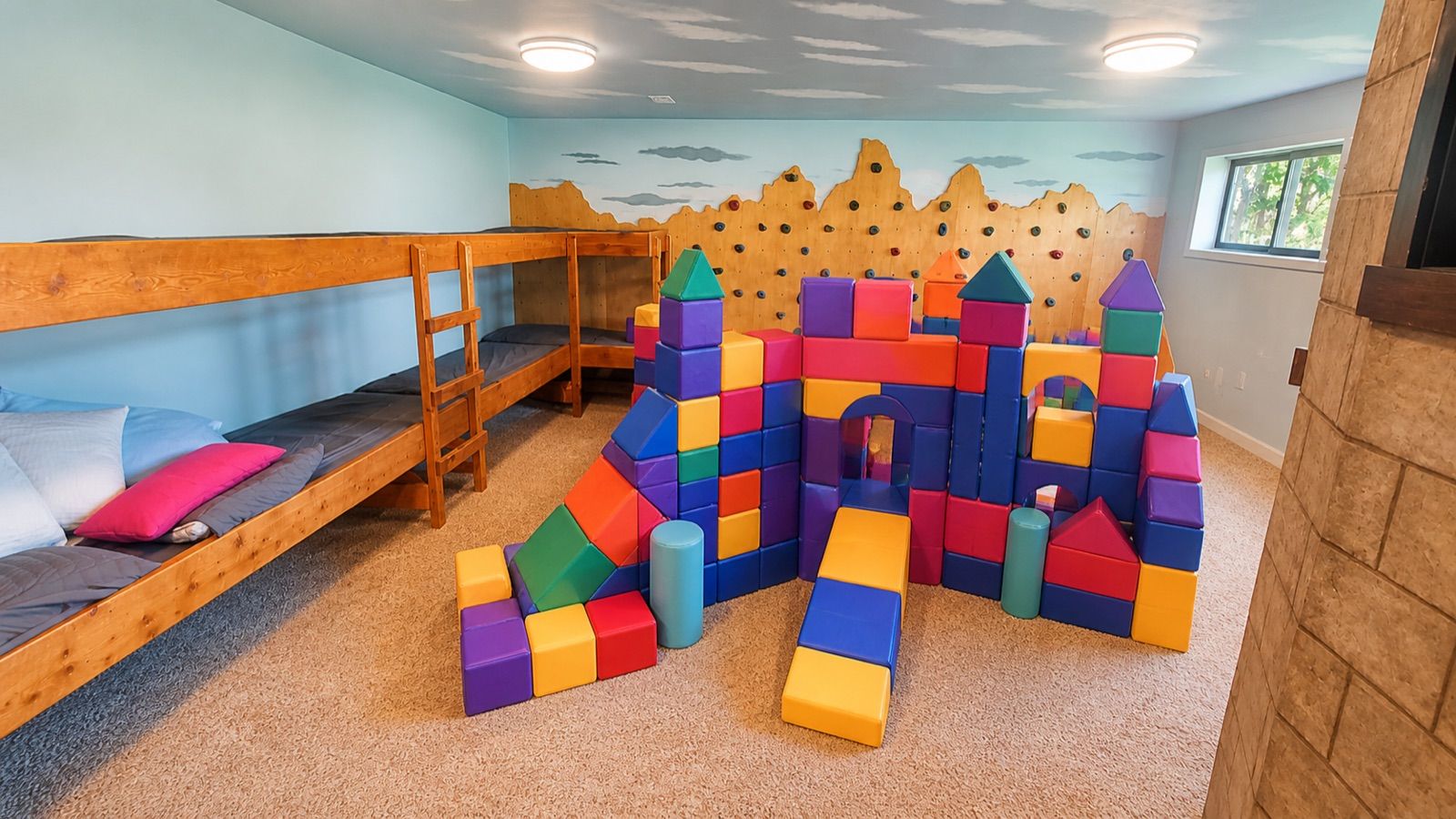 Bunk room with climbing wall, foam castle, and mountain mural