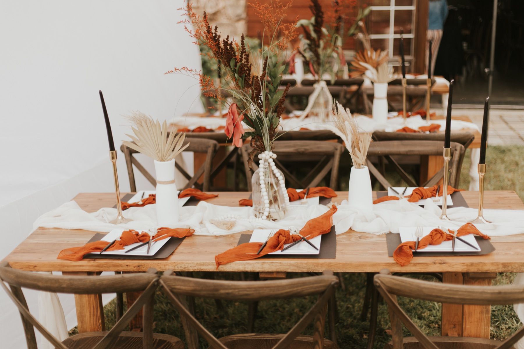 Outdoor farm table set with rust napkins and dried florals