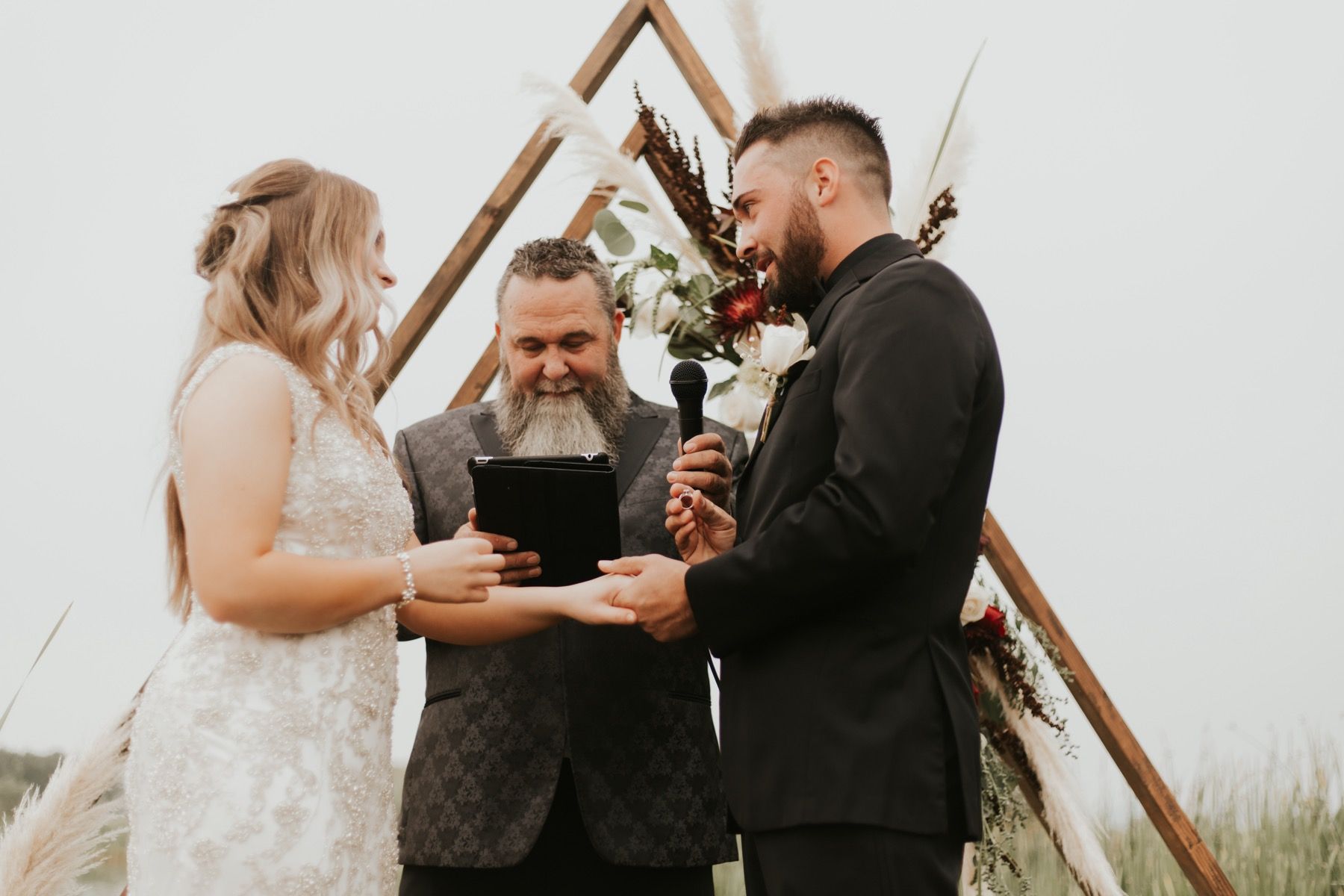 Bride and groom exchanging vows under an A-frame arch