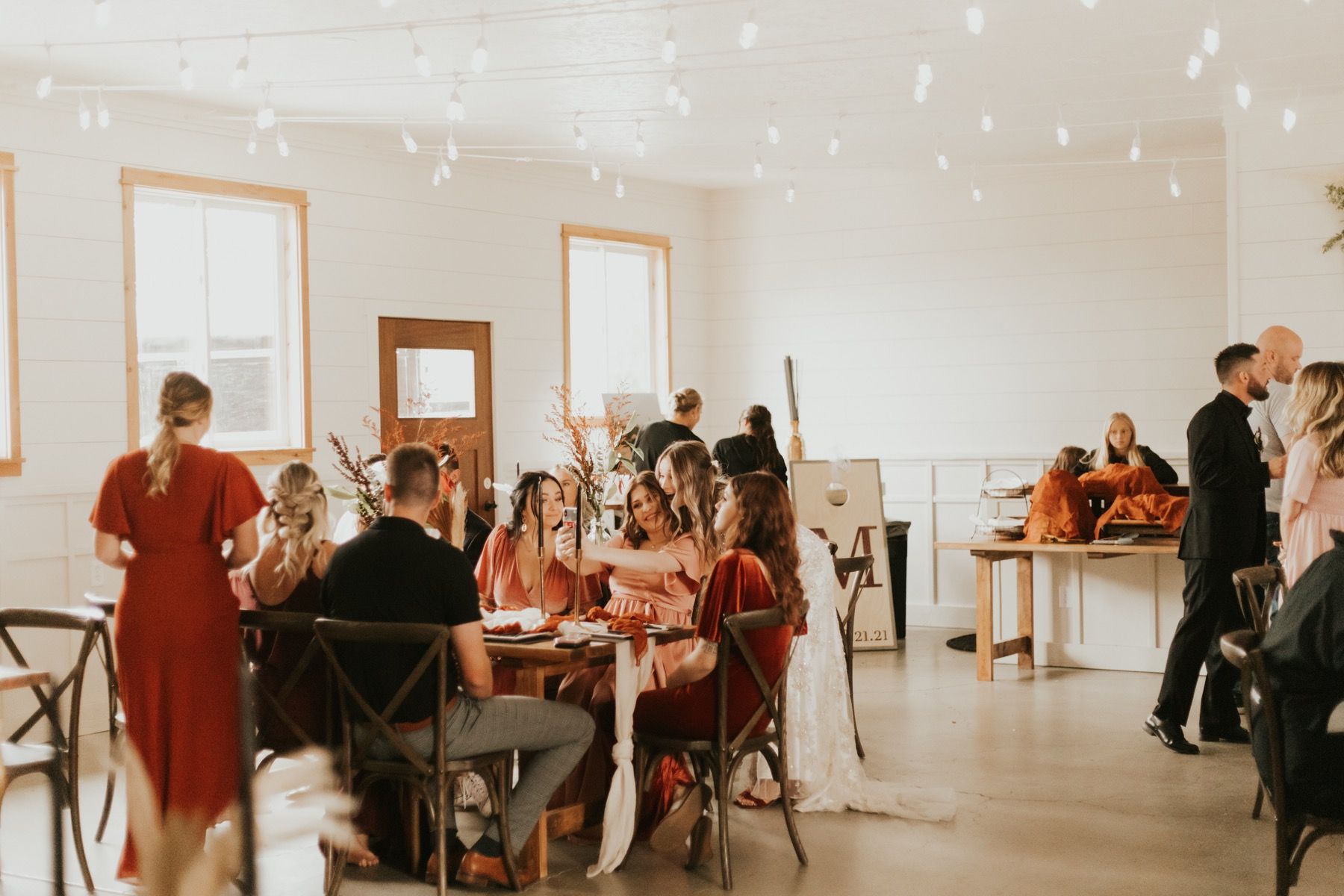 Guests at a long indoor reception table under string lights