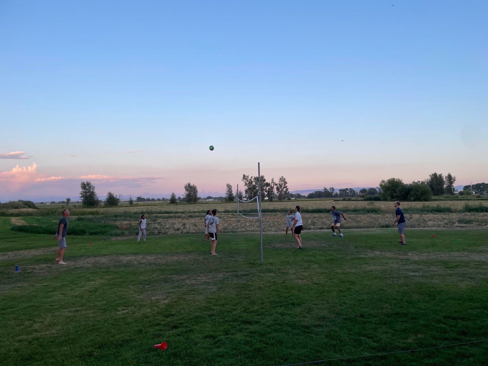Group playing volleyball on the lodge lawn at dusk