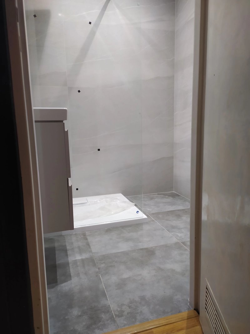 Łazienka w trakcie remontu: zainstalowany brodzik, szafka umywalkowa, wielkoformatowe marmurkowe płytki na ścianach