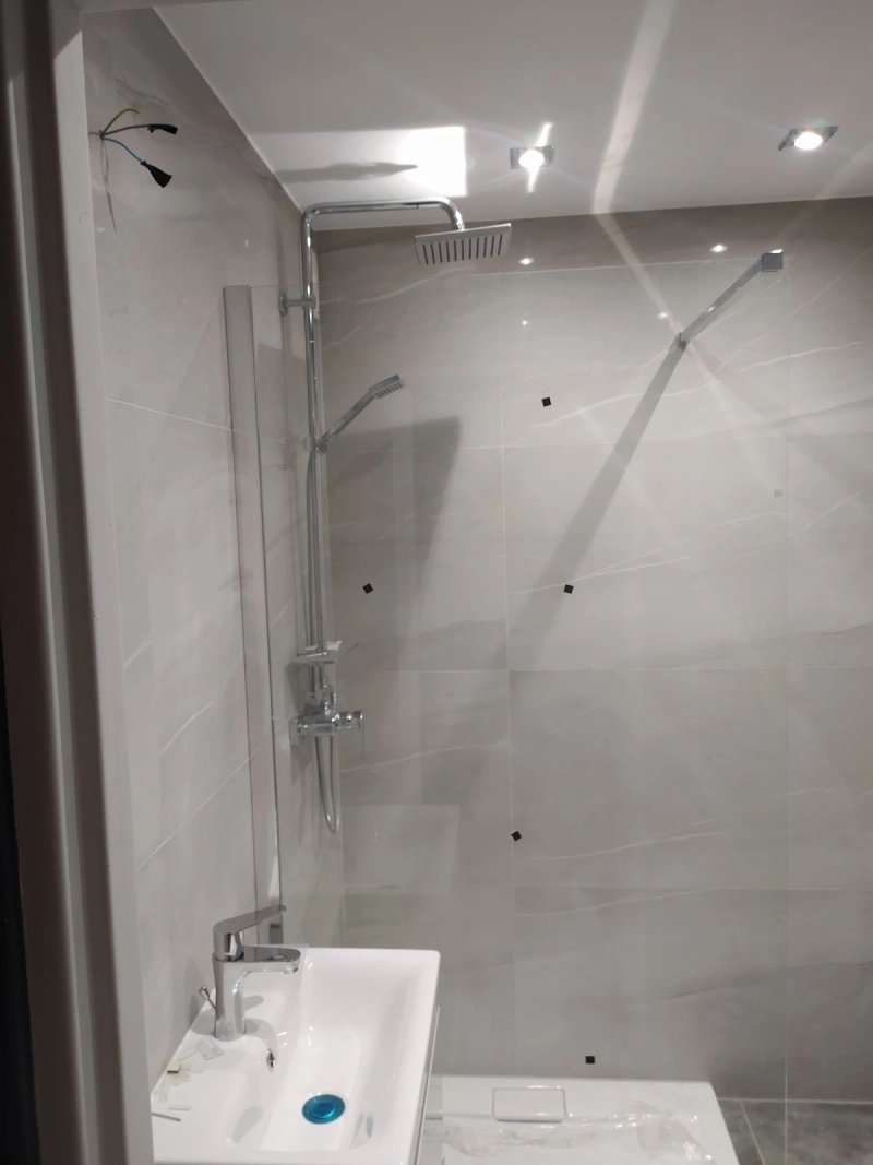 Łazienka po remoncie: prysznic walk-in z deszczownicą, wielkoformatowe płytki imitujące marmur, oświetlenie LED