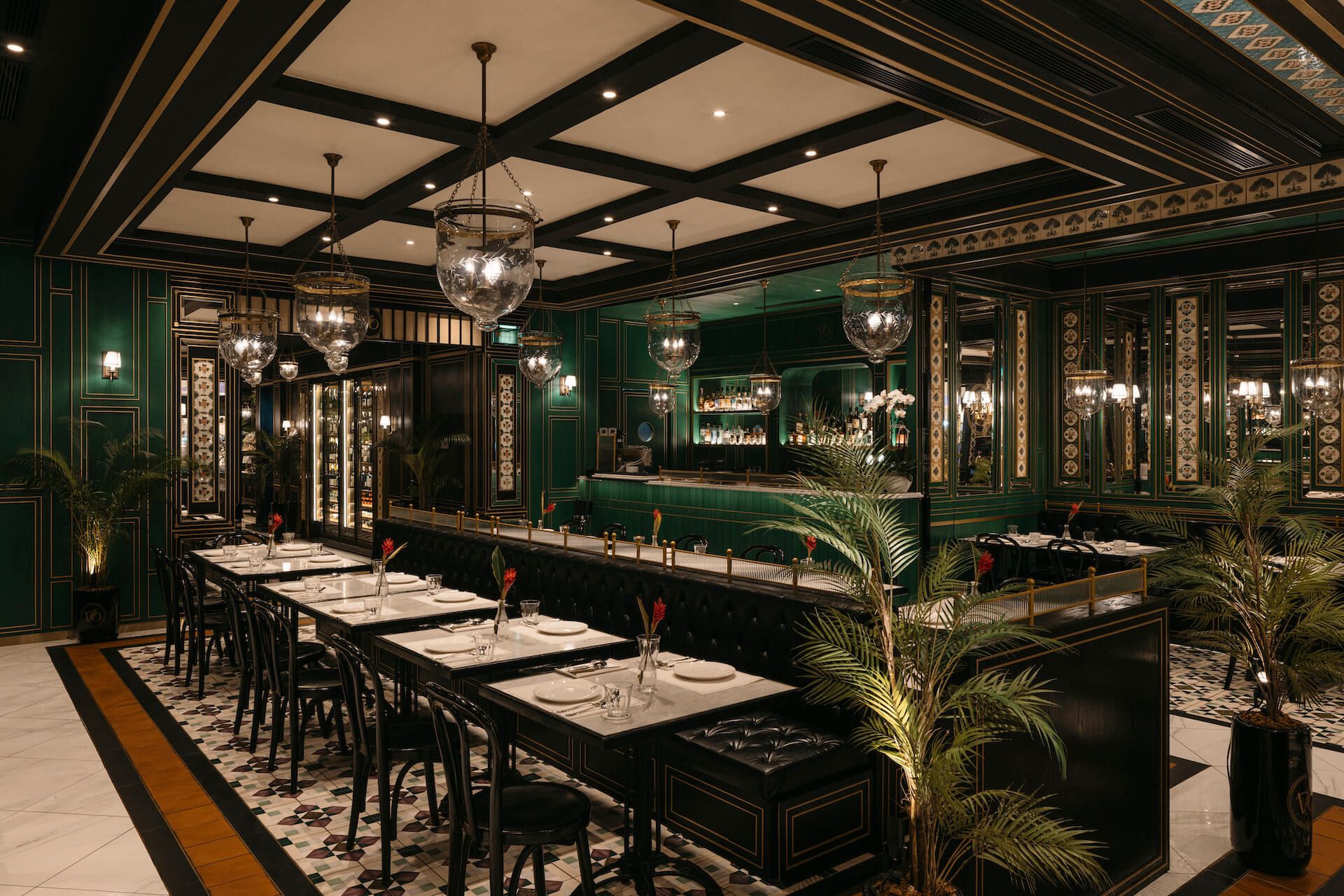 Bar and dining room with emerald green walls, crystal globe pendant lights, marble bar counter and tropical palm plants, Violet Oon at ION Orchard Singapore by LAANK