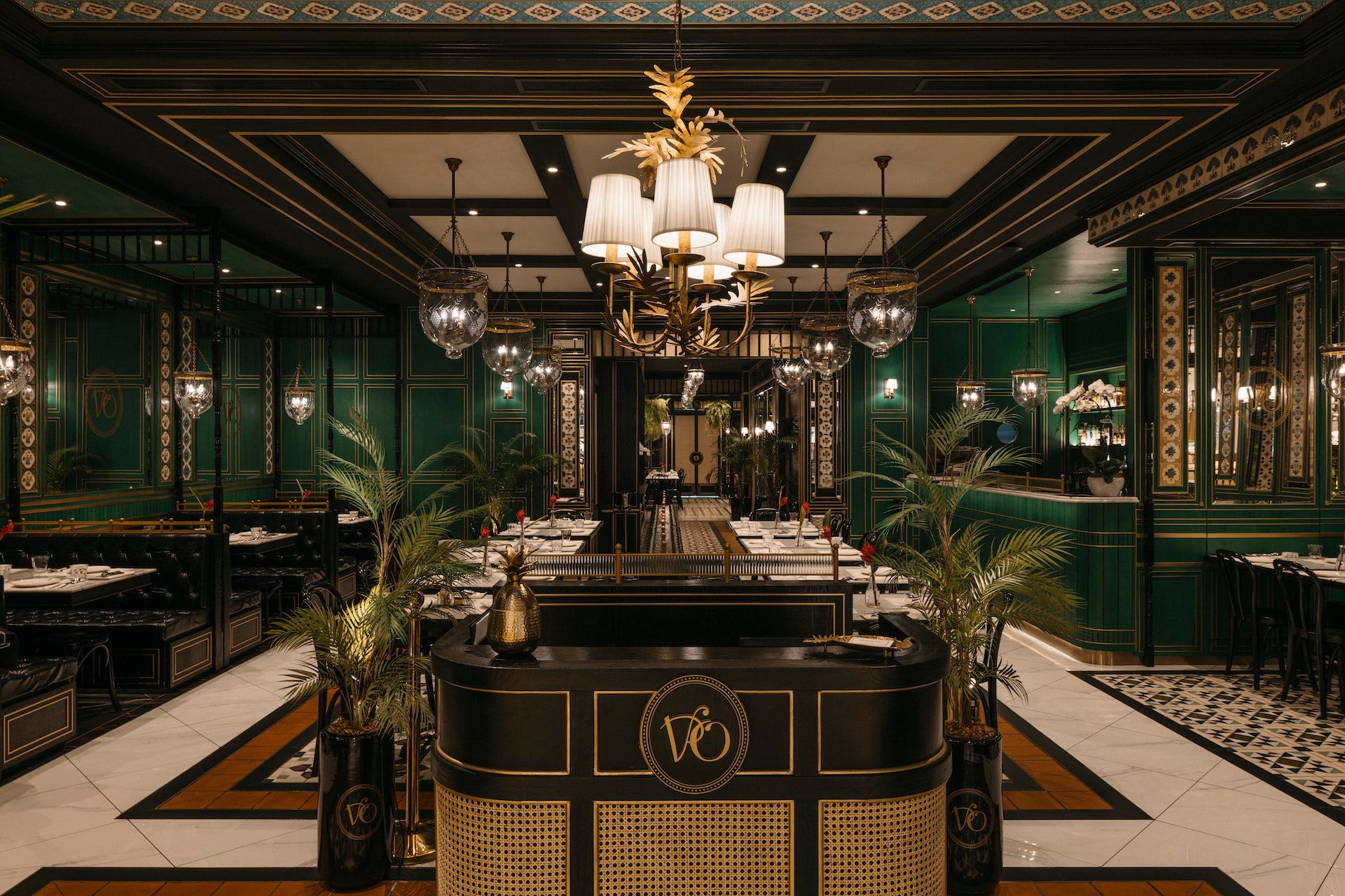 Bar and dining room with emerald green walls, crystal globe pendant lights, marble bar counter and tropical palm plants, Violet Oon at ION Orchard Singapore by LAANK
