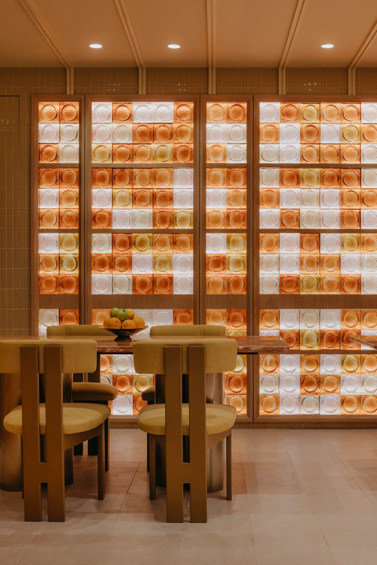 Amber glass block feature wall with timber table and olive green upholstered chairs, The Marmalade Pantry at ION Orchard Singapore by LAANK