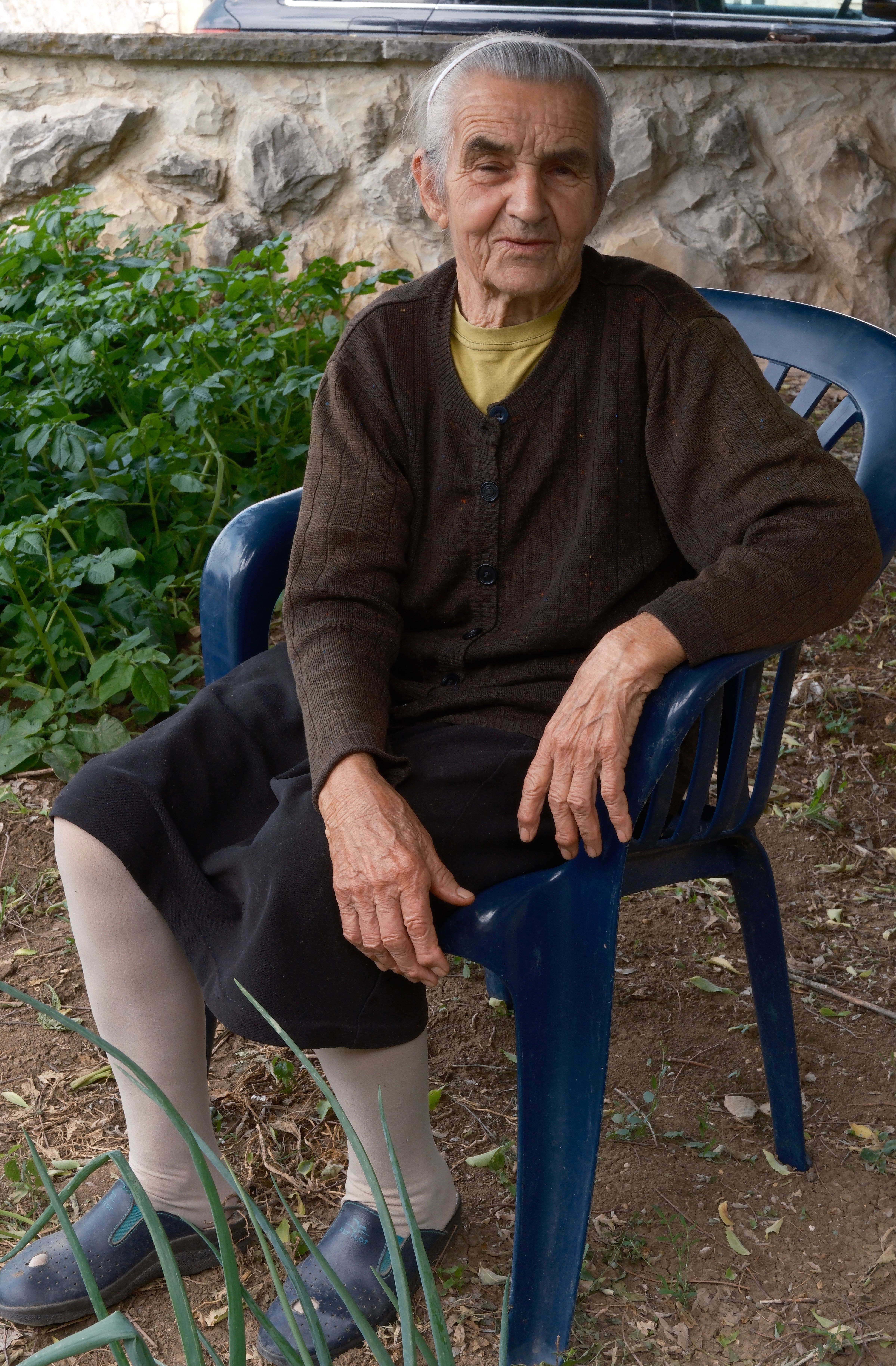 Portret bake koja sjedi u bašti, simbol tradicije i marljivosti porodice Jokić.