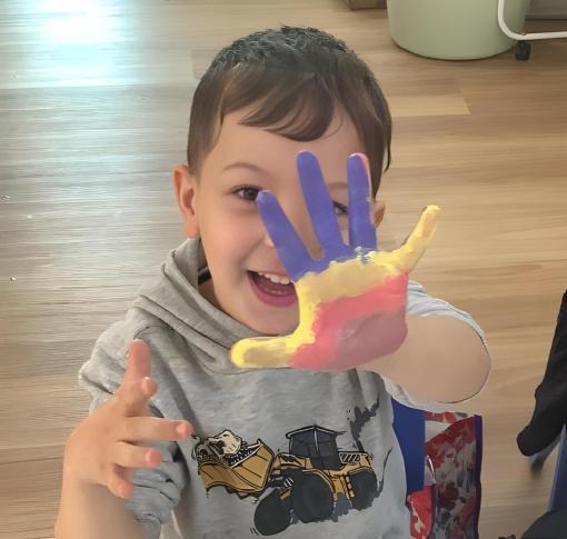 A happy child with paint on their hands at First Foundation Preschool