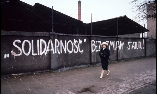 Woman walking past a graffiti wall 