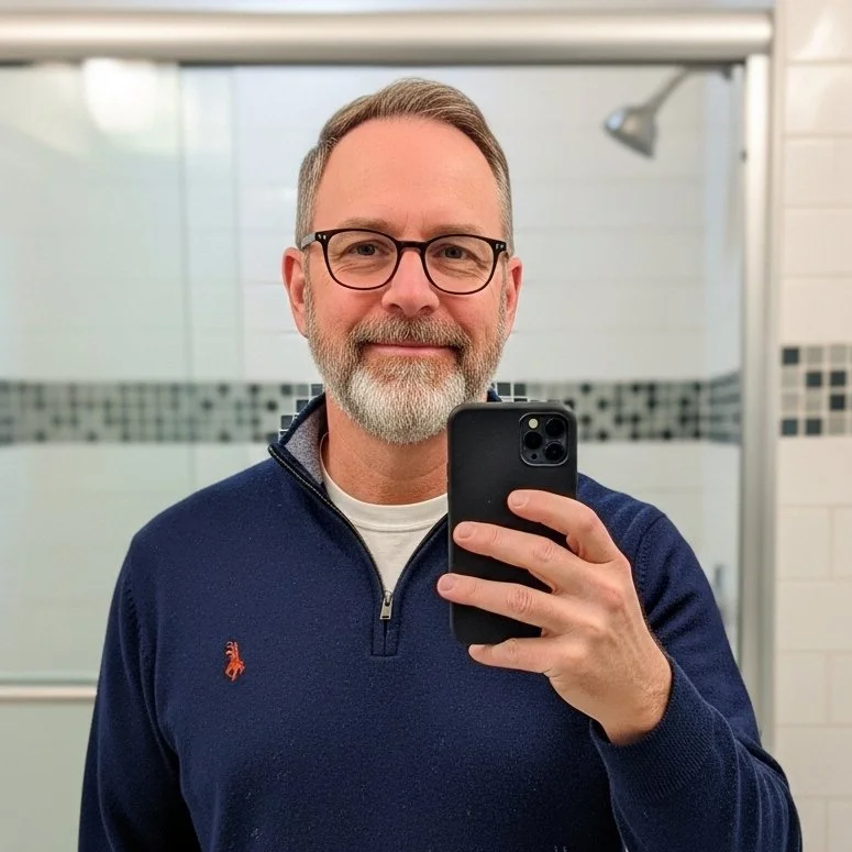 Image_fx+(1).png A man with glasses and a beard taking a selfie in a bathroom mirror.
