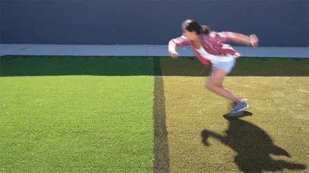 A woman sprinting across a lawn where the grass changes from dry brown to lush green.