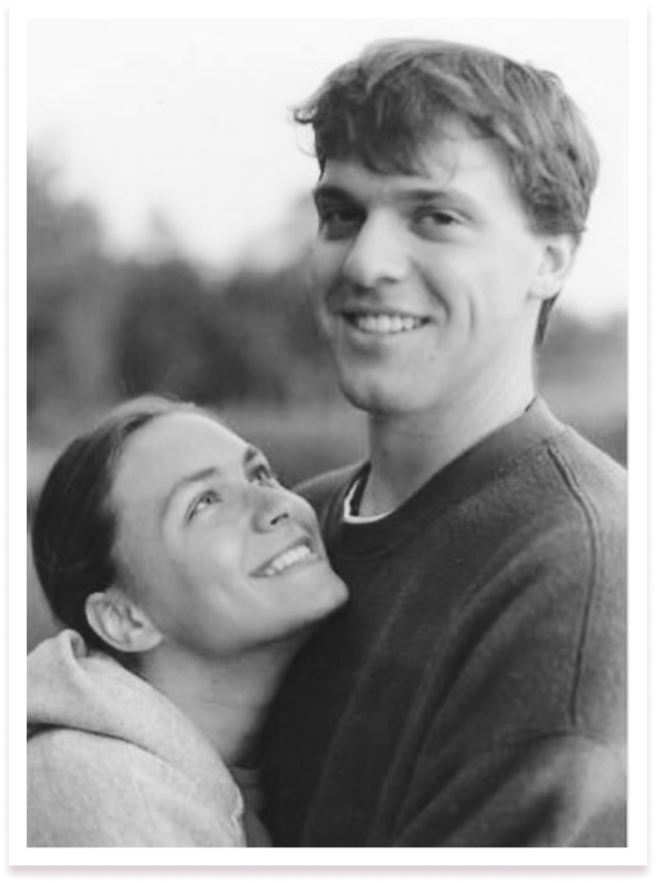 Image-11.png A cheerful black and white photo of a young couple, with the woman looking up affectionately at the smiling man, outdoors.