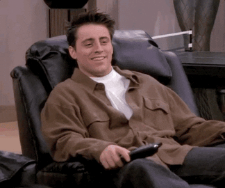 Sad+Season+2+GIF+by+Friends.gif A man in a brown jacket laughs while relaxing in a leather recliner, holding a remote control.