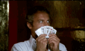 cards+juking+GIF.gif A man in a white robe peers over a fanned hand of playing cards held up to his face.