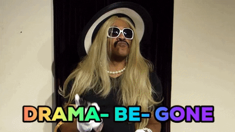 75dce93d-299f-c788-0474-675647372cb6.gif A performer in a blond wig, sunglasses and white gloves gestures as colorful text reads 'Drama be gone.'