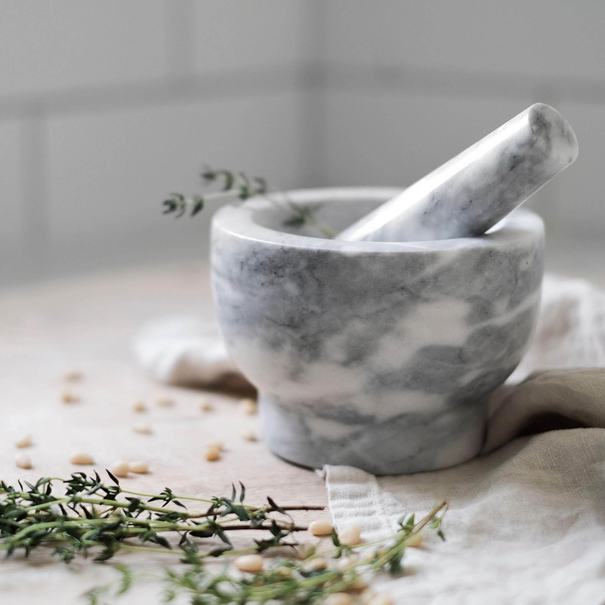 a marble mortar and pestle with thyme in it