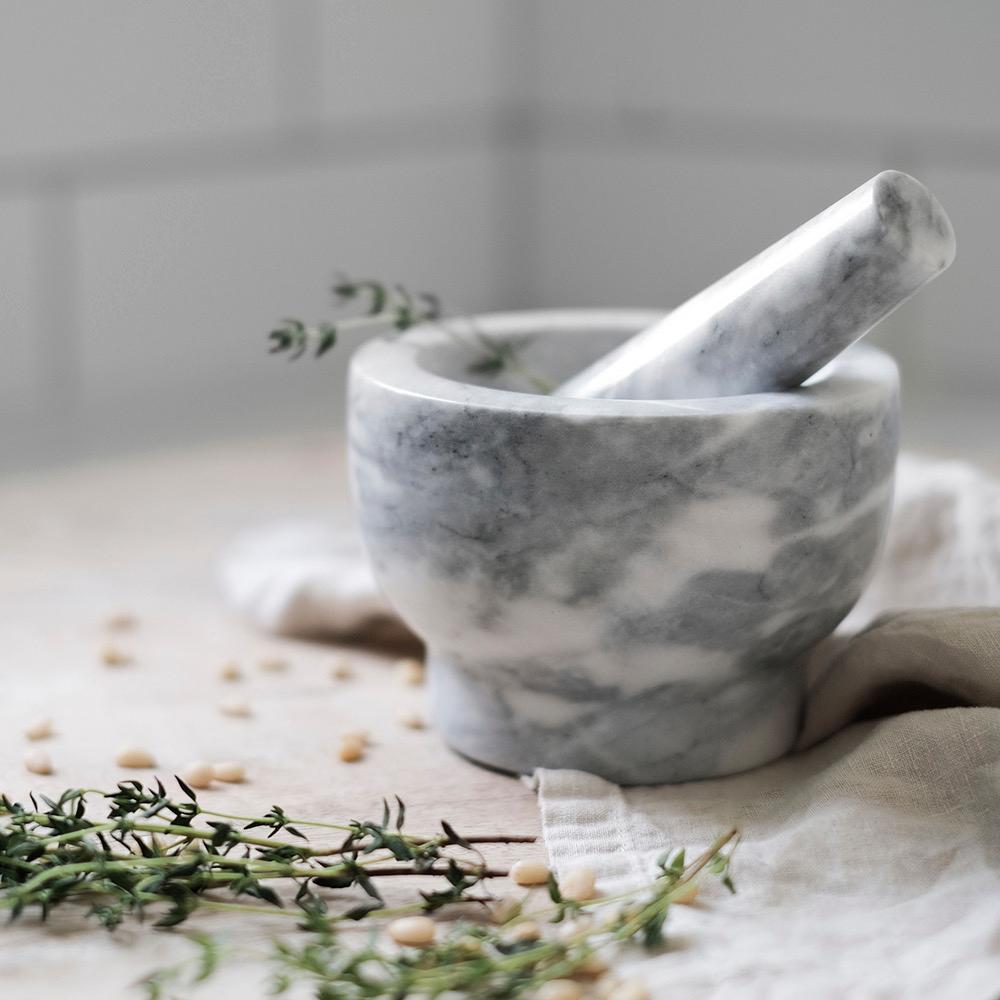 a marble mortar and pestle with thyme in it