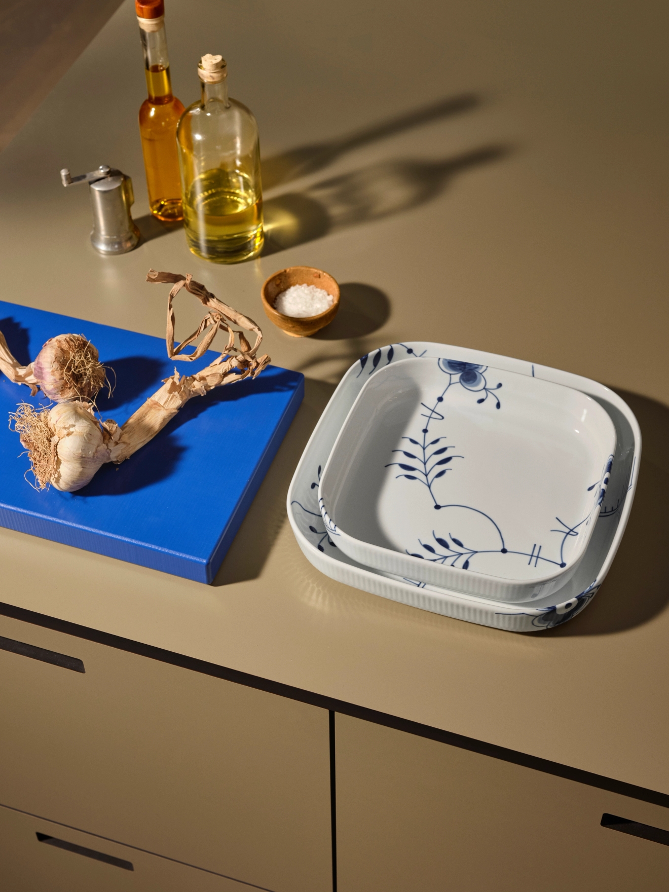 Vita fyrkantiga tallrikar på bänk med blå skärbräda