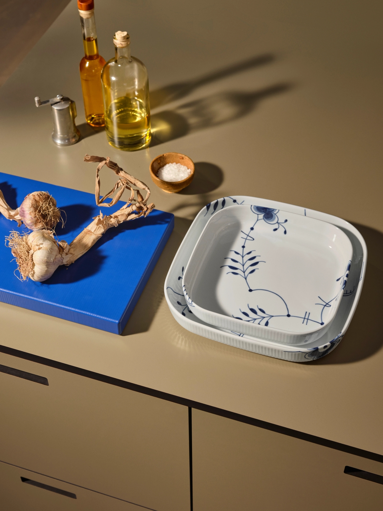 Vita fyrkantiga tallrikar på bänk med blå skärbräda