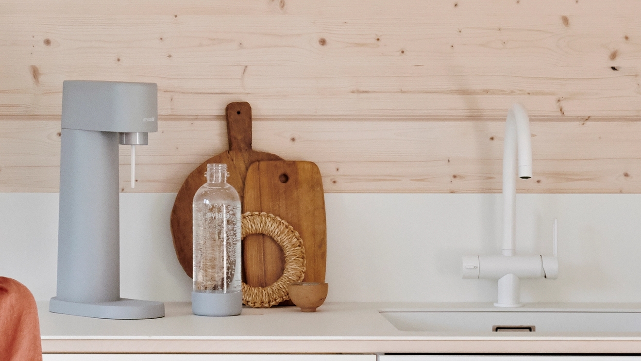 Harmaa Mysoda Woody hiilihapotuslaite ja pullo valkoisella keittiön työtasolla