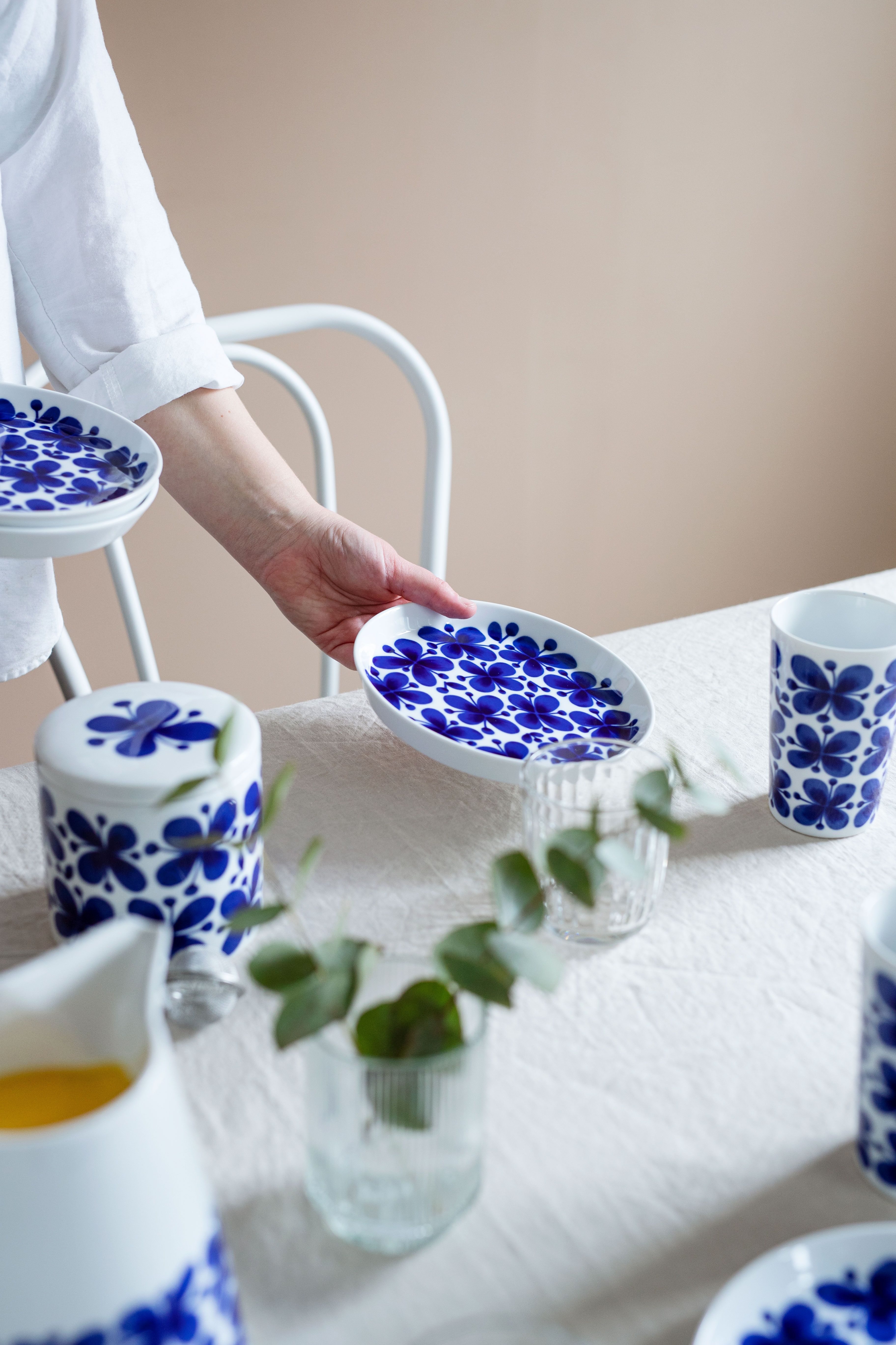 En person ställer en Mon Amie assiett på ett bord med en vit linneduk