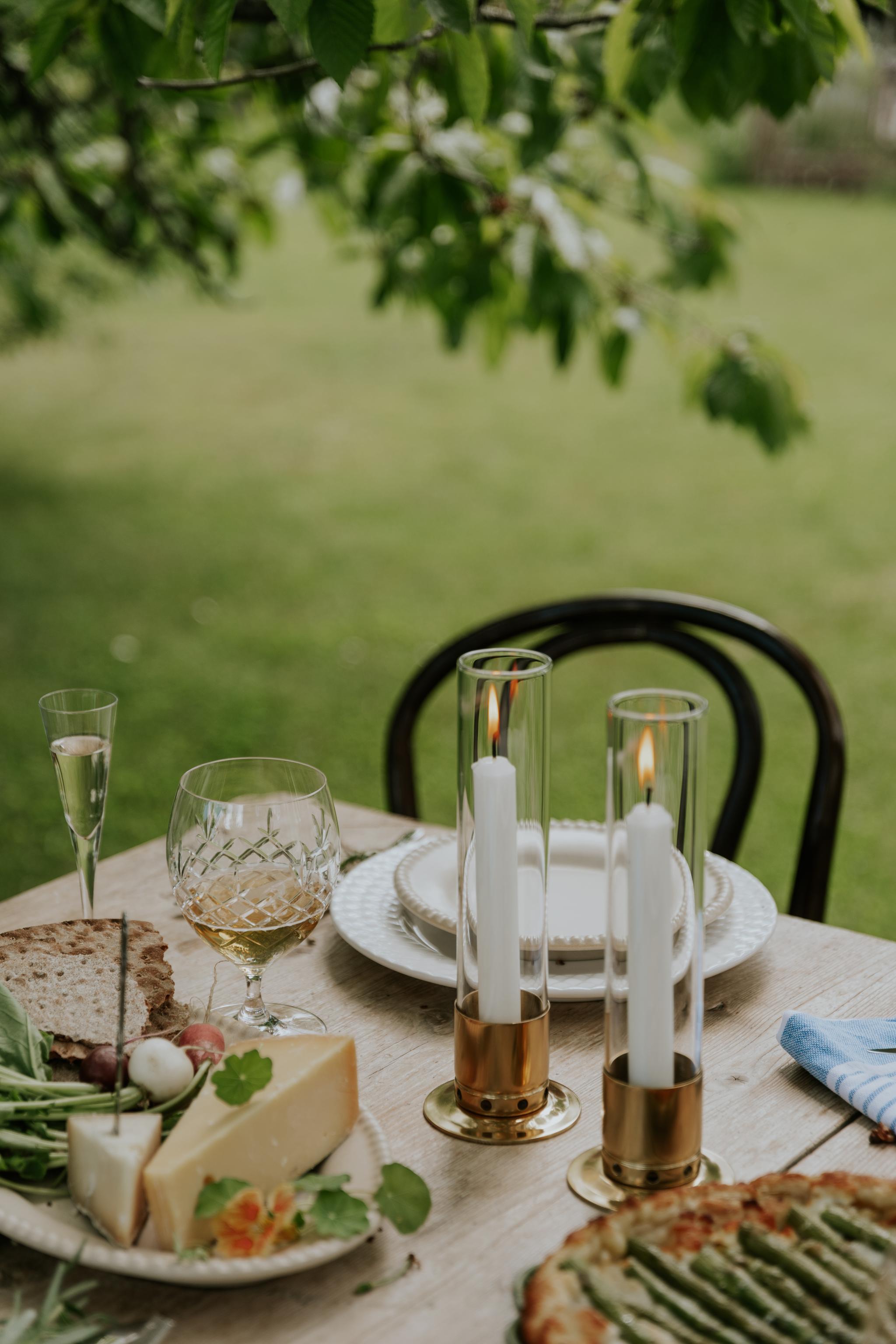 Pöydän kattaus rapujuhliin juustotarjotin tarjoilulautanen kynttilälyhdyt kynttilät juustopiirakka viinilasit snapsilasit