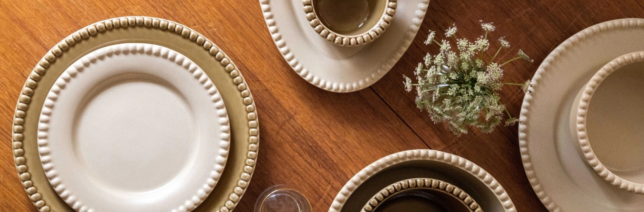 erikokoiset ja eriväriset lautaset ja kulhot puisella pöydällä