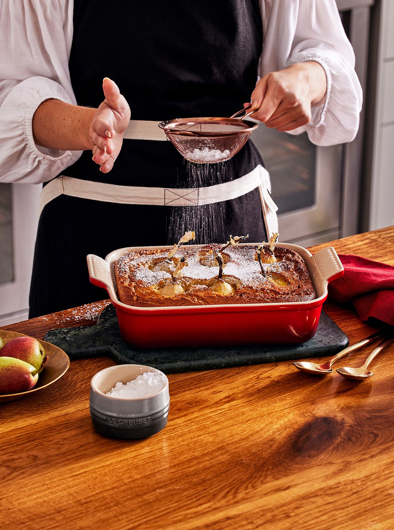 Nainen sirottelee kakun päälle tomusokeria