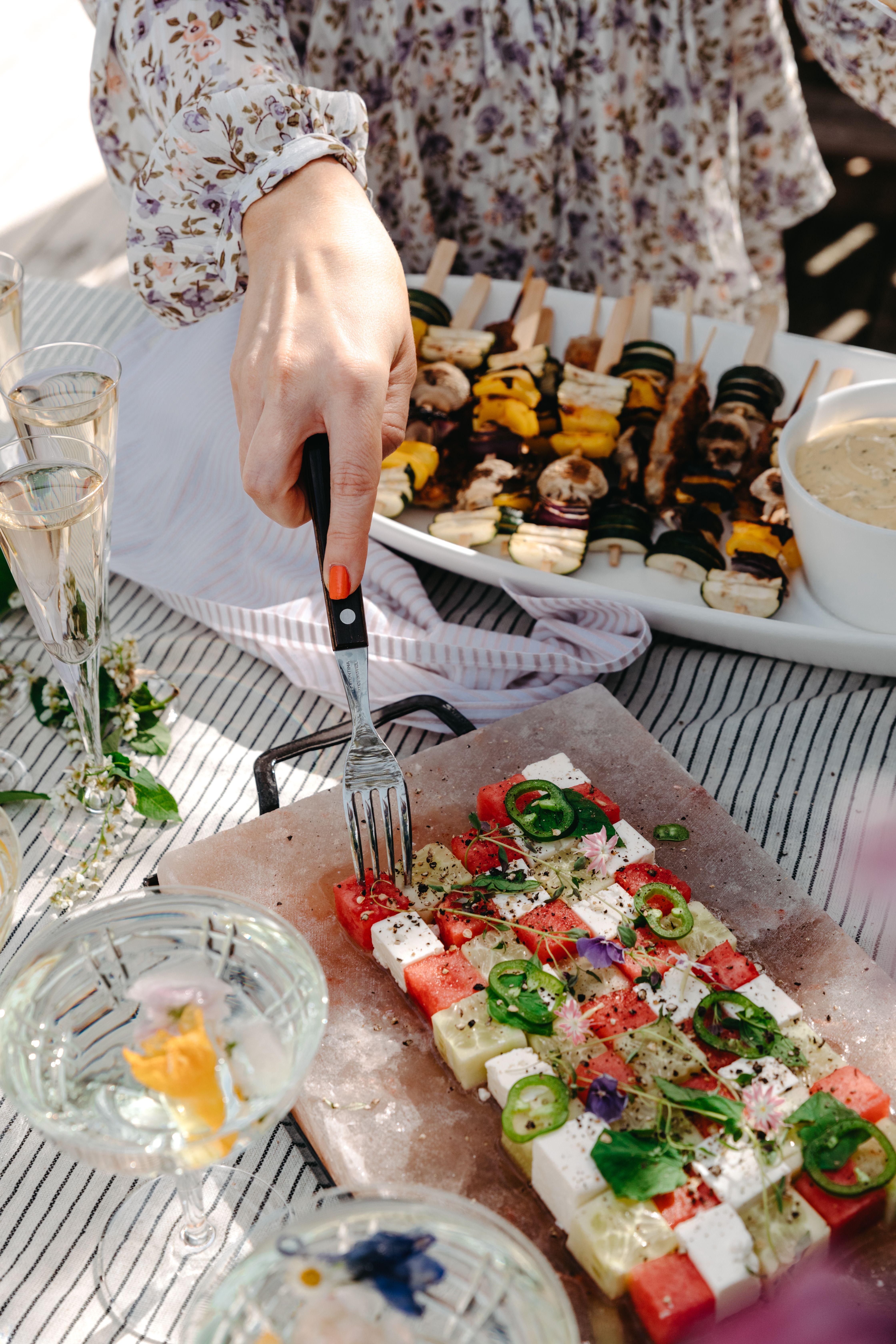 Grillspett och sallad med melon och fetaost på ett somrigt bord
