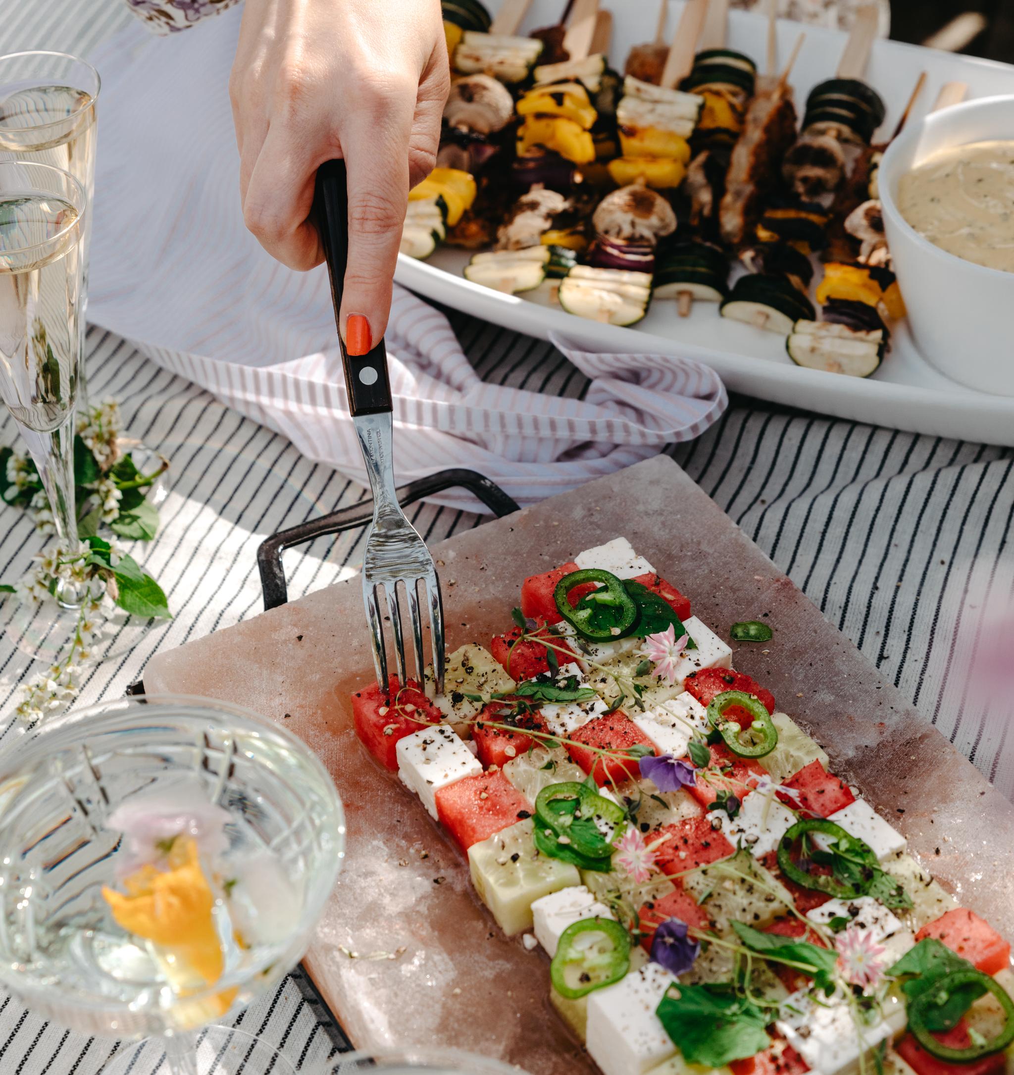 Grillspett och sallad med melon och fetaost på ett somrigt bord